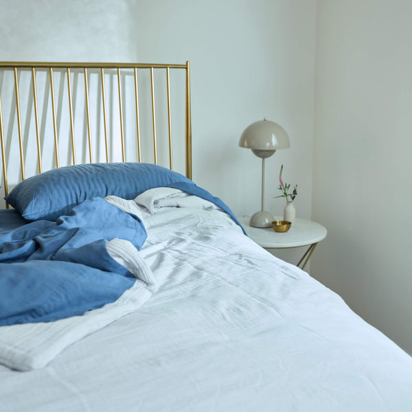 An Avec Goods Cotton Quilt and Classic Linen Sheet Set on a bed with the morning sun shining on it