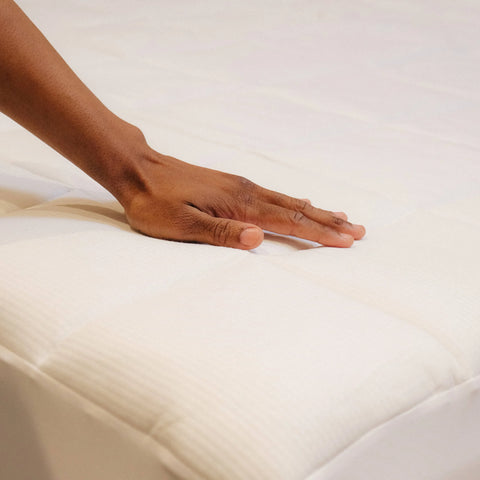 A man touching the outer fabric of the Slumber Cloud Performance Mattress Pad