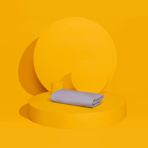The Slumber Cloud Performance Duvet Cover with temperature regulation technology and Tencel to help you stay cool through the night on a yellow pedestal.